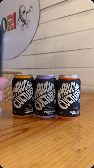 Latas de kombucha artesanal frente al logo de Colori
